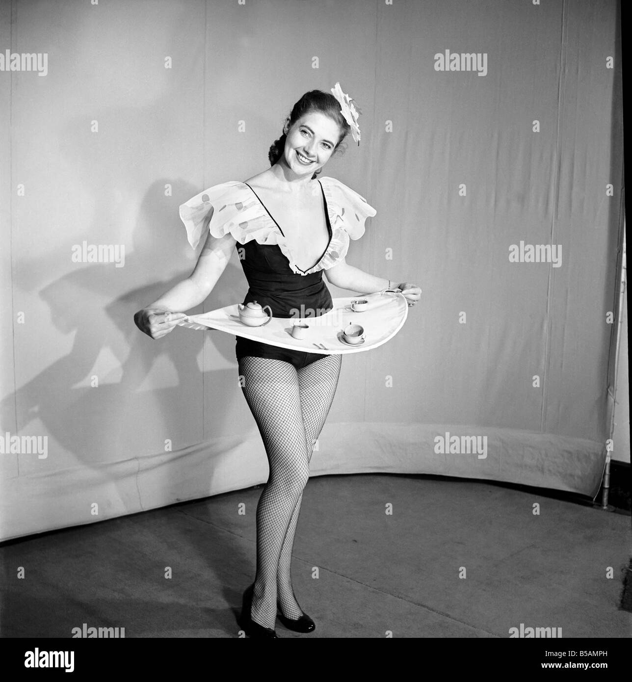 Donna che indossa un mantello che è anche un vassoio, visto qui con bollitore e tazze sul vassoio. 1959 Foto Stock