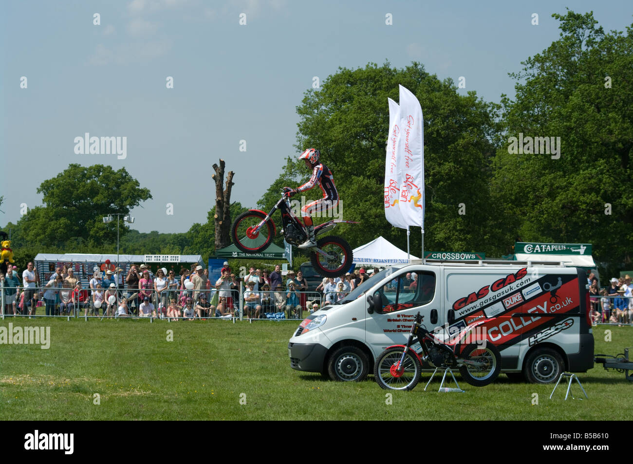 Motociclista acrobatico equitazione sulla sua moto saltando su un veicolo Cowpie Rally Betchworth Surrey eseguono acrobazie Foto Stock