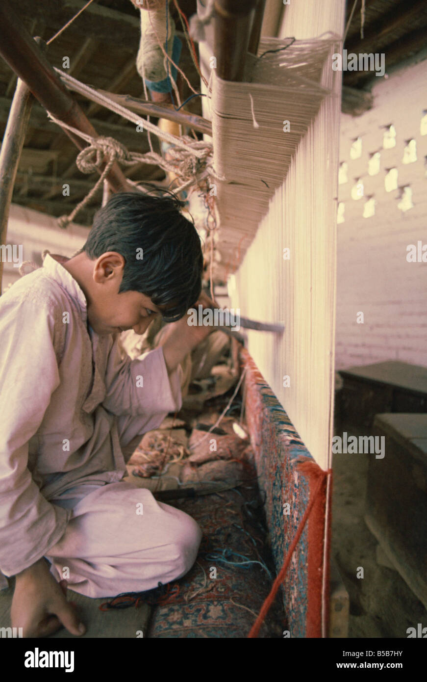 Bambino a lavorare nella fabbrica di tappeti negli anni settanta a Lahore in Pakistan Asia Foto Stock