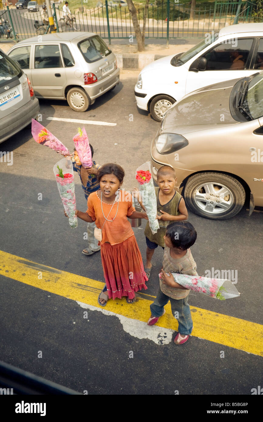 I bambini poveri sulle vie di Delhi che vendono fiori per fare soldi; New Delhi, India Foto Stock