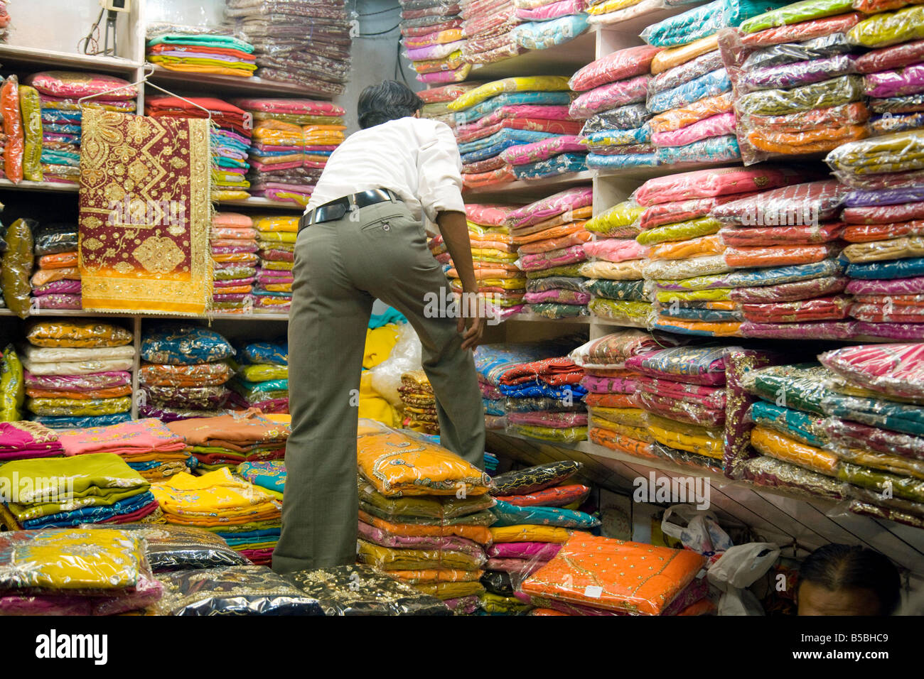 Un bottegaio cerca un sari, il mercato Kinari, 'Old Delhi' India Foto Stock