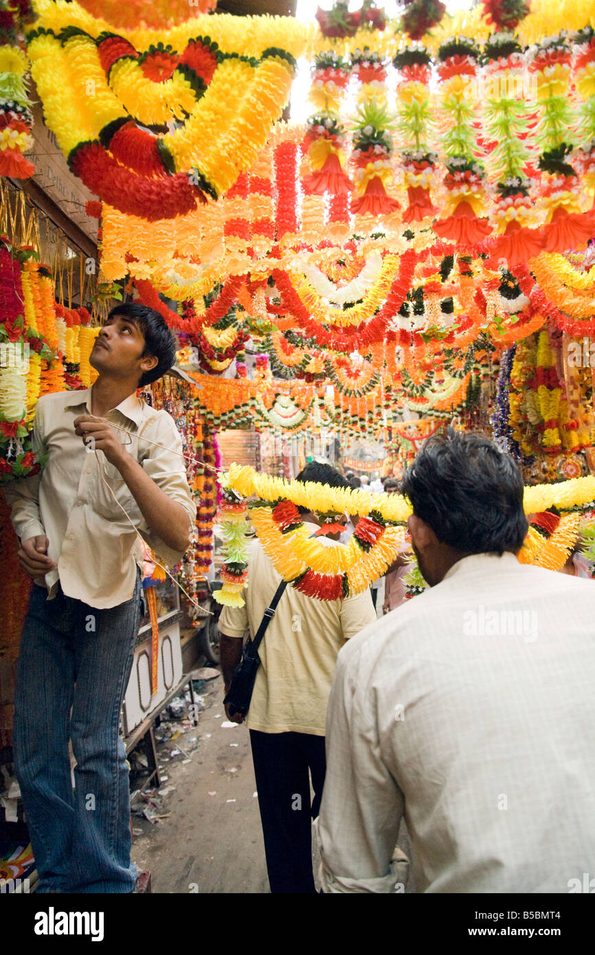 Un bottegaio appendere ghirlande colorate nel mercato Kinari, 'Old Delhi' India Foto Stock
