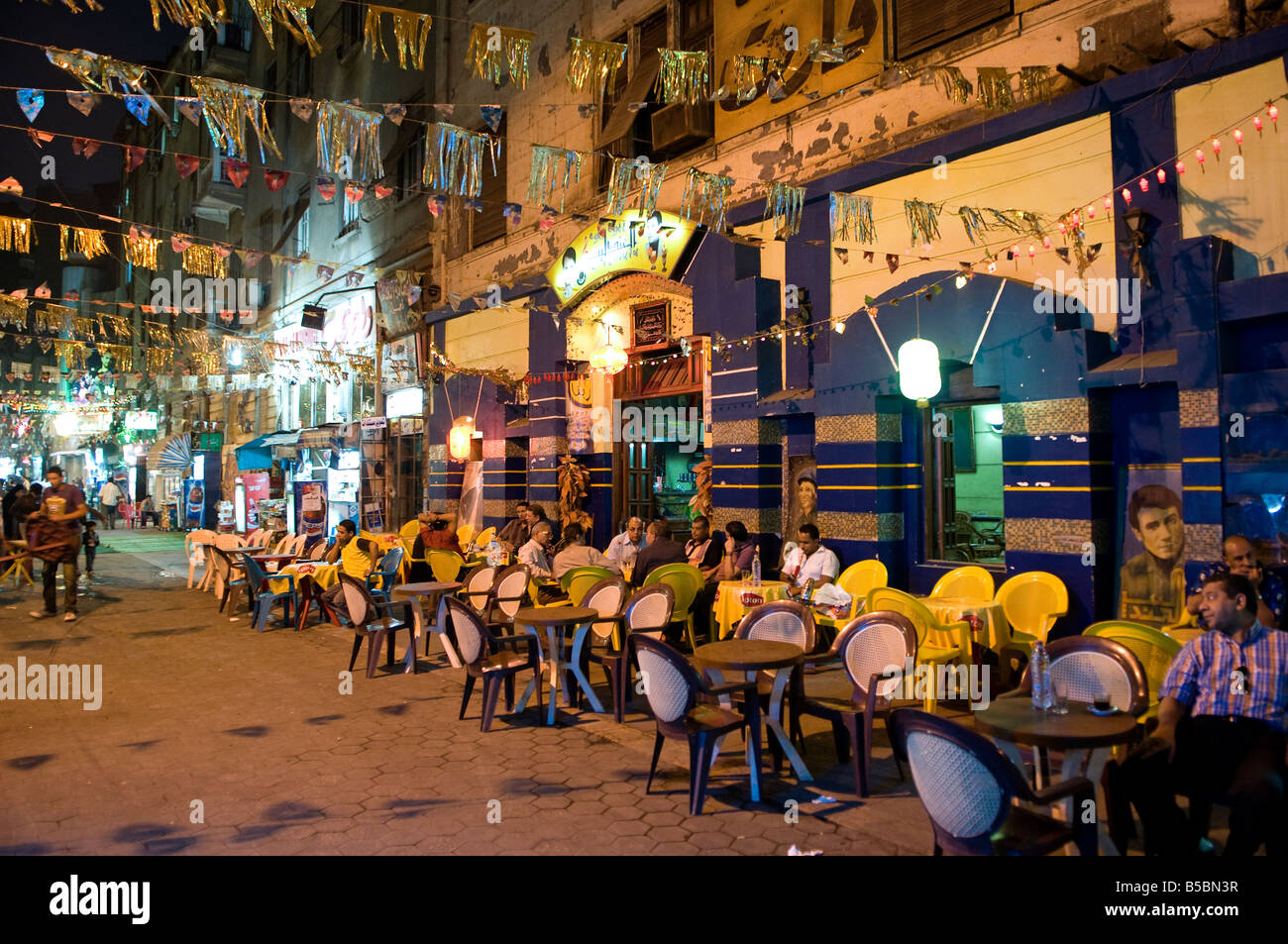 Una strada ricca di caffetterie e ristoranti con persone sedute a tavoli fuori in centro cittadino del Cairo in Egitto Foto Stock