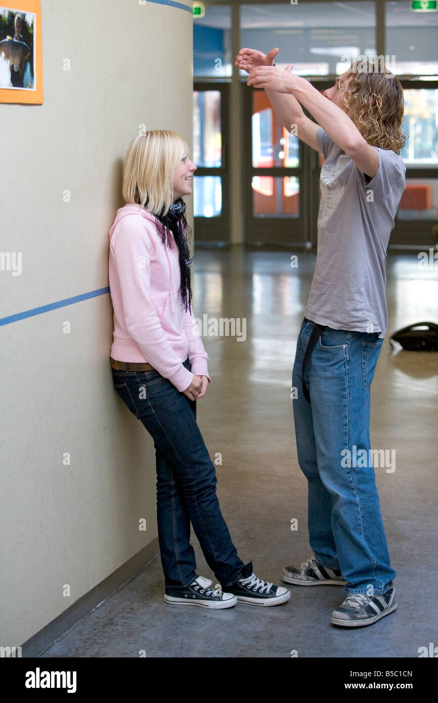 Ragazzo adolescente e una ragazza parlando nella hall della scuola Foto Stock