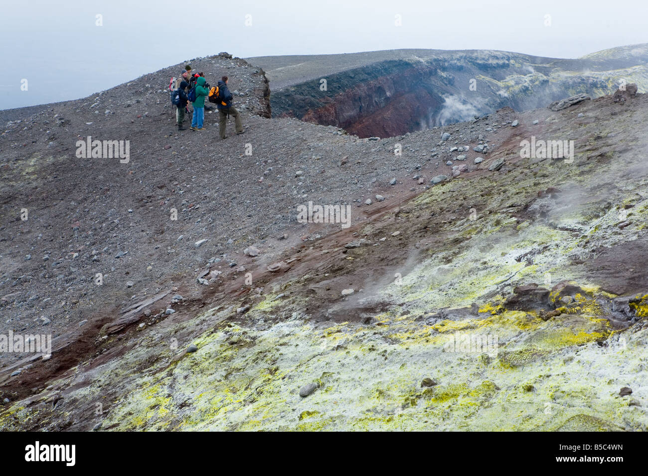 Gruppo di escursionisti in piedi sul bordo del fumo Mt. Il vulcano Etna la Bocca Nuova cratere Foto Stock