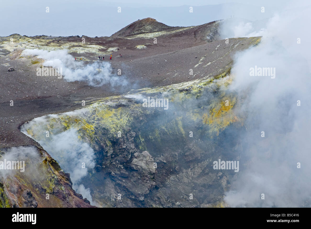 Gruppo di tiny-guardando gli escursionisti dentro la Bocca Nuova, il cratere del vulcano Etna Foto Stock