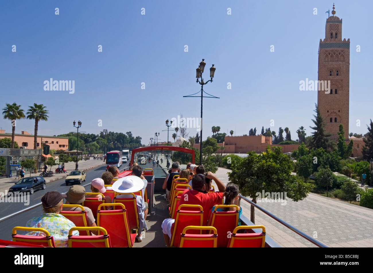 Il piano superiore di un organizzato autobus turistico tour intorno a Marrakech con la Moschea di Koutoubia minaret sulla destra. Foto Stock