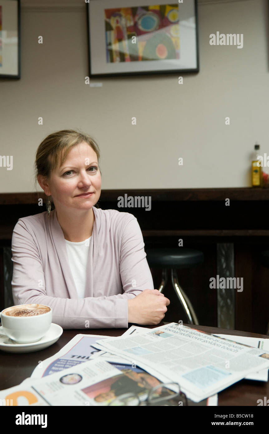Samantha Wynne Rhydderch, giovane donna gallese poeta iscritto in inglese, seduta in cafe leggendo il giornale di bere il caffè Foto Stock