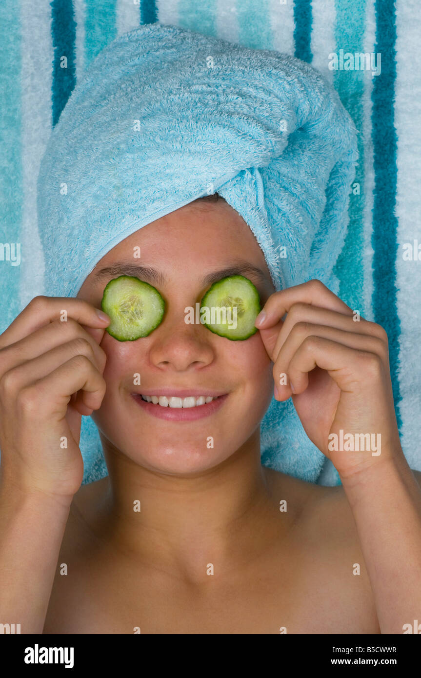 Una graziosa adolescente dà di se stessa un trattamento beaty ponendo le fette di cetriolo sopra i suoi occhi Foto Stock