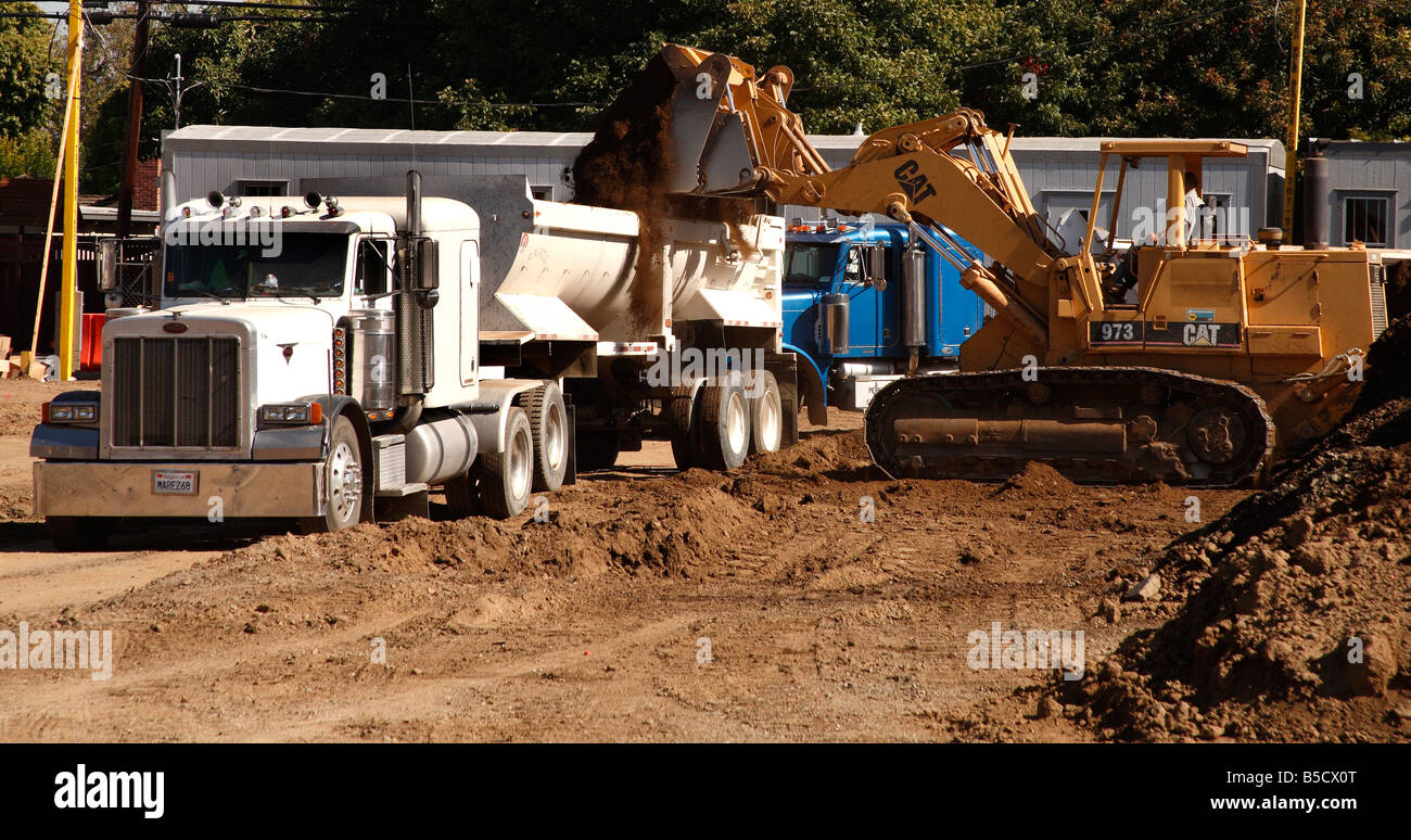 Caterpillar 973 pratiche di dumping sporcizia nel semi rimorchio camion a Bascom biblioteca e centro comunitario sito in costruzione Foto Stock