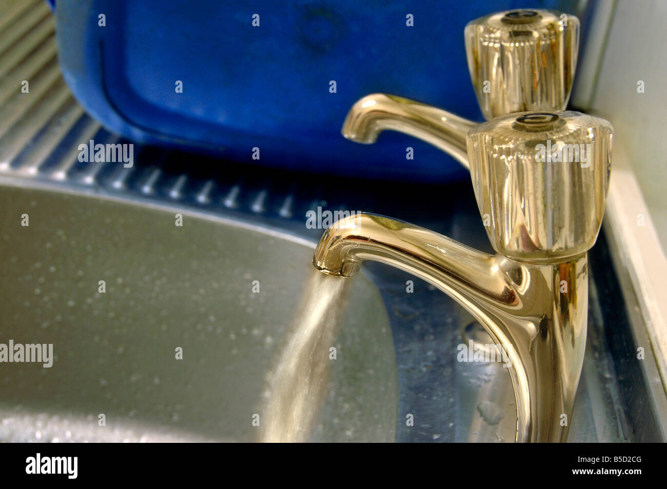 Esecuzione di acqua da un rubinetto al lavello. Foto Stock