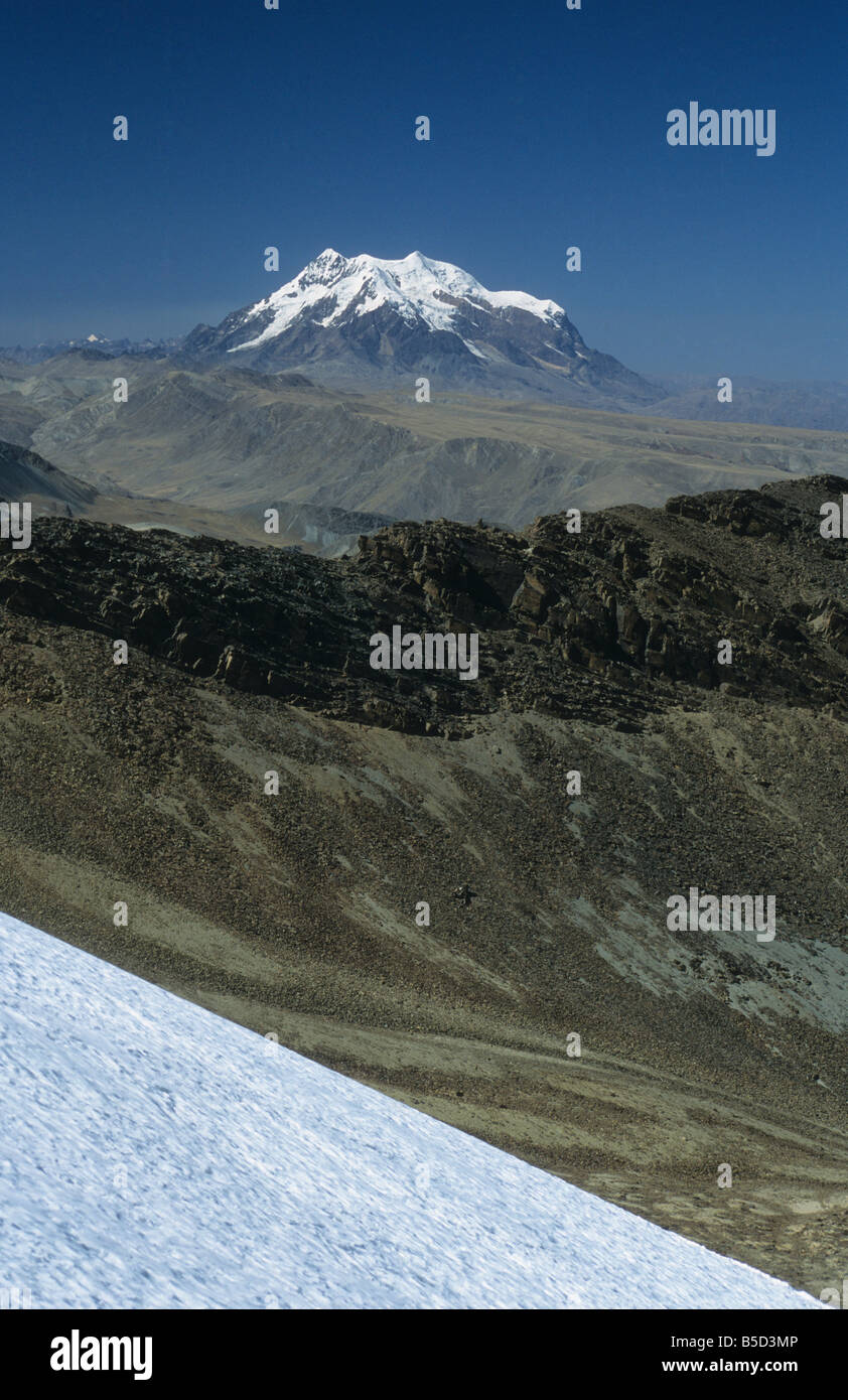 Mt Illimani visto da Mt. Chacaltaya stazione ghiacciaio, scree pendici sottostanti al crinale a metà distanza, Cordillera Real, Bolivia Foto Stock