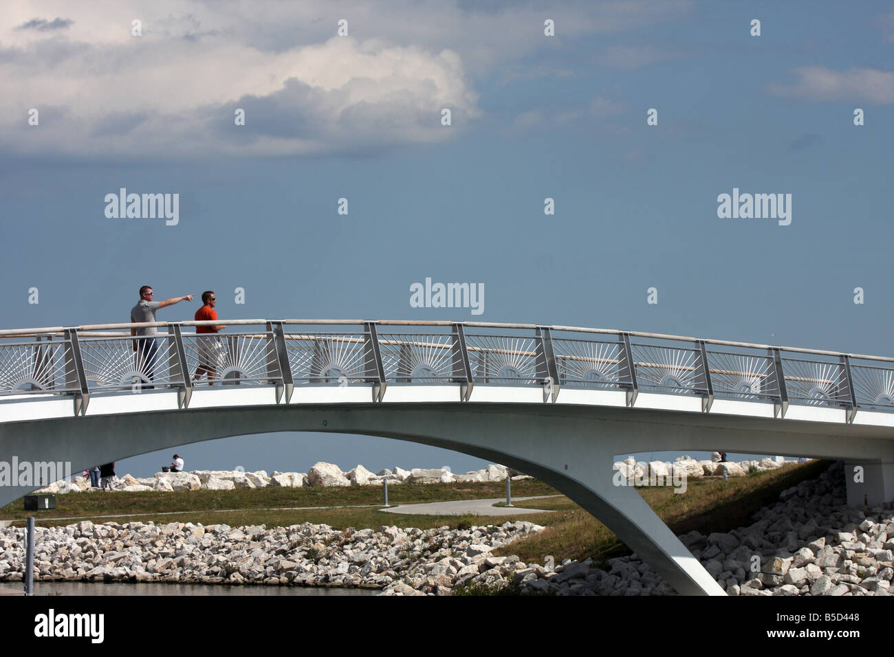 Un ponte al di sopra della baia di fronte al lago con due veggenti sito camminando su di essa della penisola di Milwaukee e del Lago Michigan Foto Stock