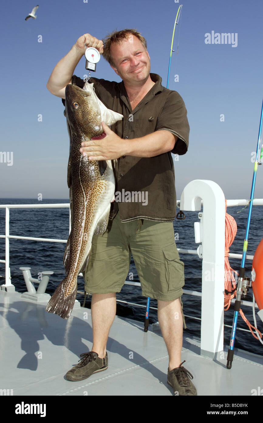 Un orgoglioso pescatore che mostra un appena pescato baccalà Foto Stock
