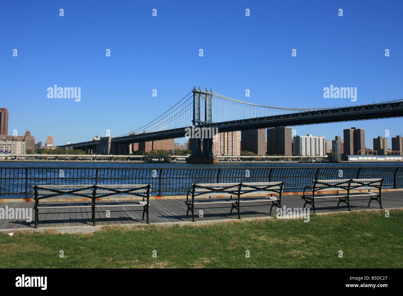 Panchine lungo la East River a Brooklyn. Manhattan Bridge in background. Foto Stock