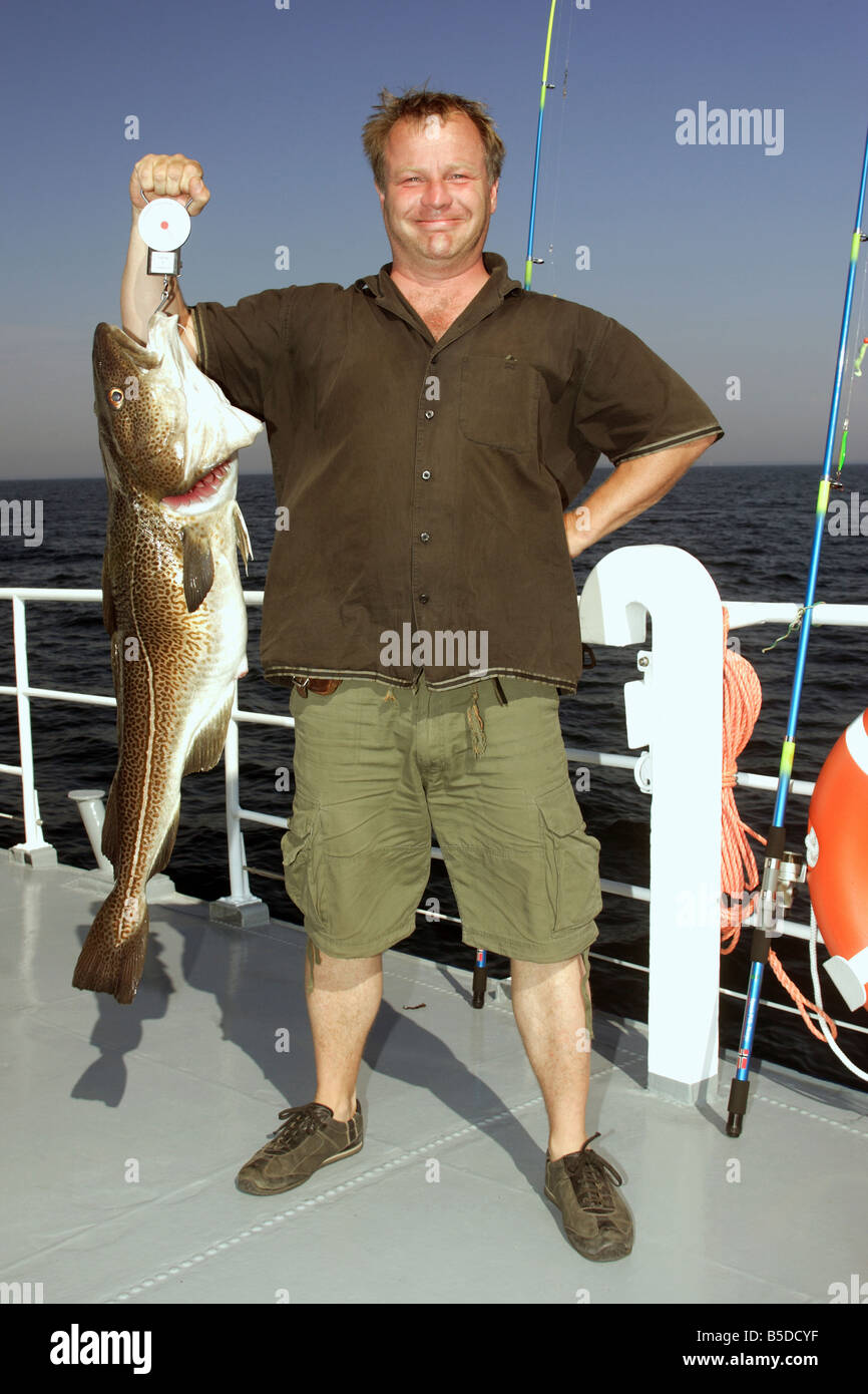 Un orgoglioso pescatore che mostra un appena pescato baccalà Foto Stock