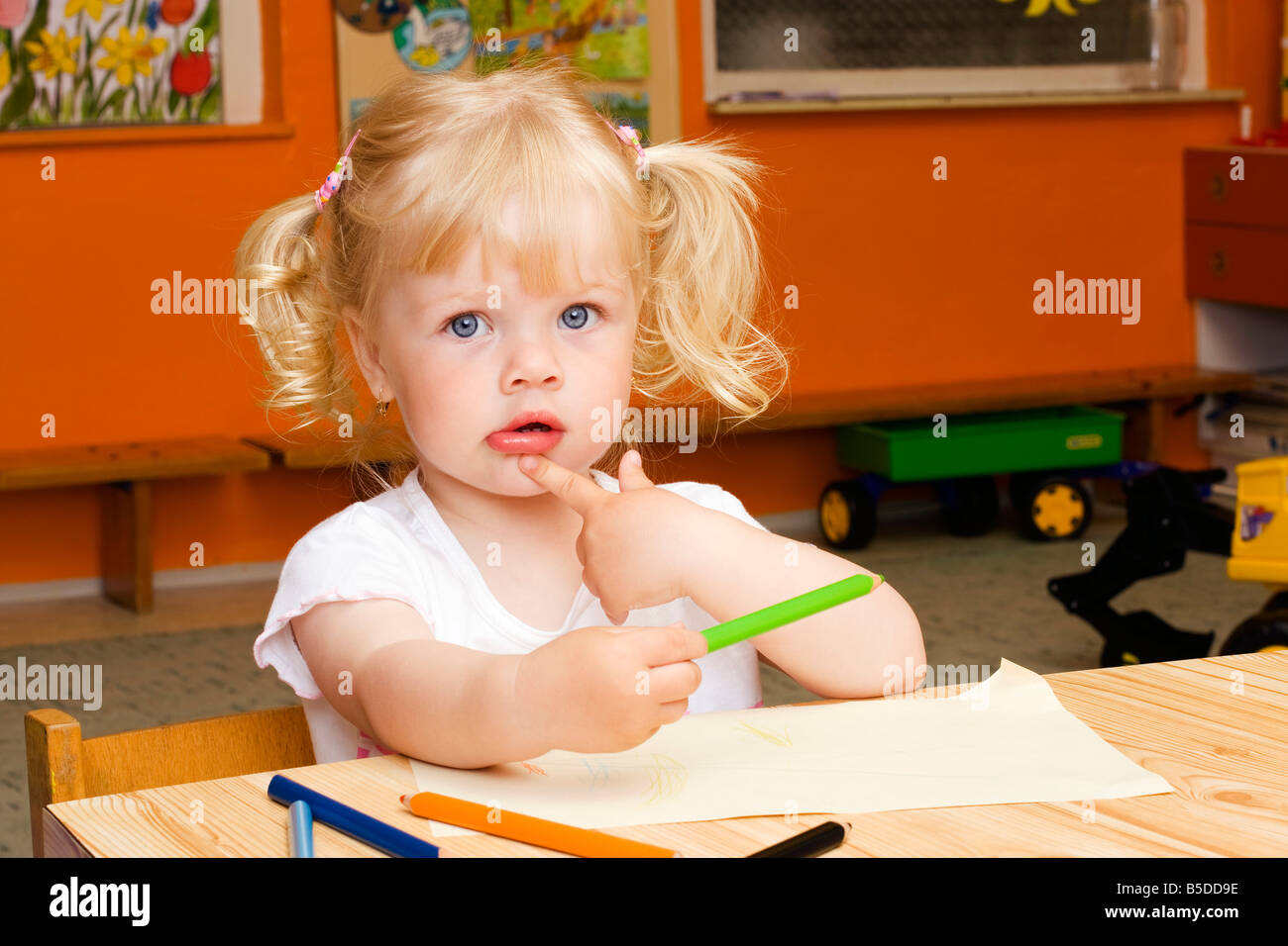 La bionda bambina di 2 anni, seduta a tavola con matite colorate Foto stock  - Alamy