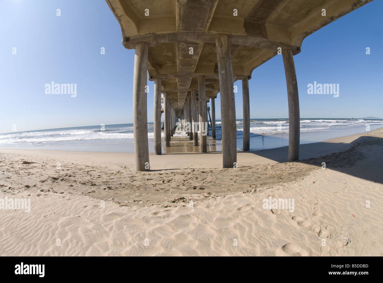 Una foto della parte inferiore di un molo mostra la prospettiva ampia di una scena di spiaggia Foto Stock