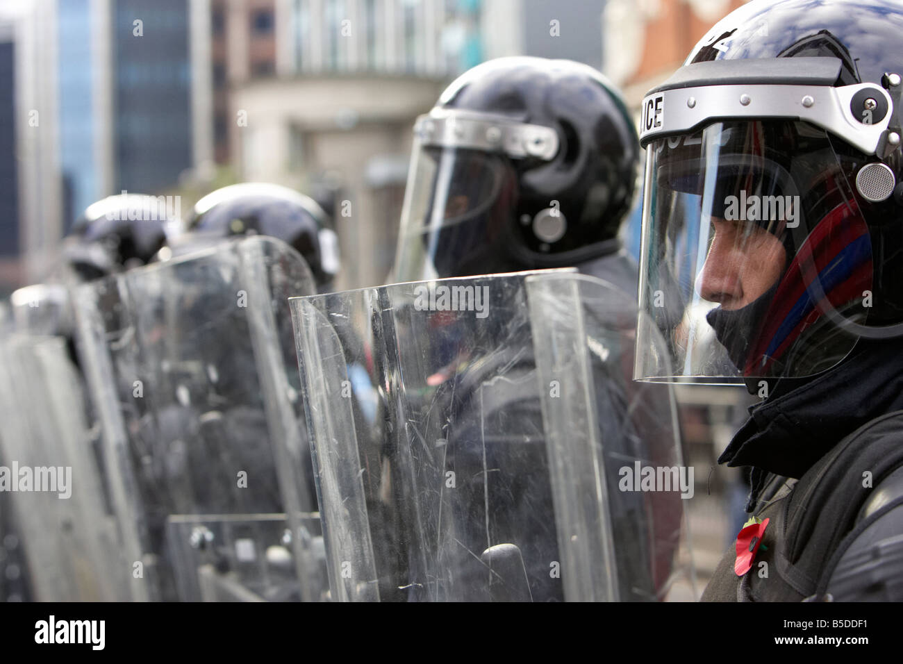 Linea di PSNI Servizio di Polizia dell'Irlanda del Nord riot ufficiali formano una barriera protettiva con scudi antisommossa durante il turbamento bel Foto Stock