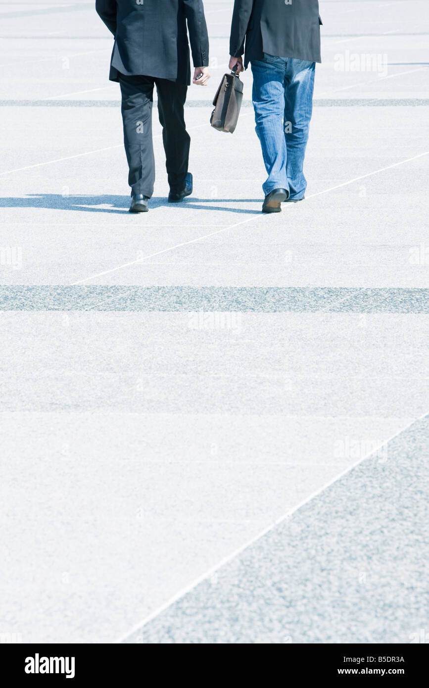 Due imprenditori camminare insieme indossare abbigliamento business, uno che indossa jeans con Blazer Foto Stock
