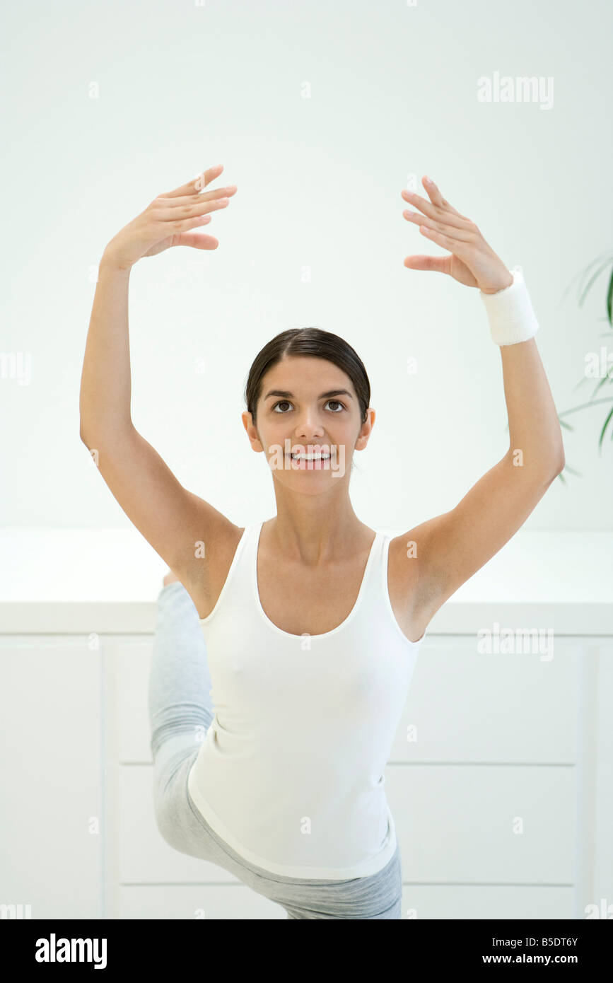 Donna stretching, braccia alzate e una gamba dietro lei Foto Stock