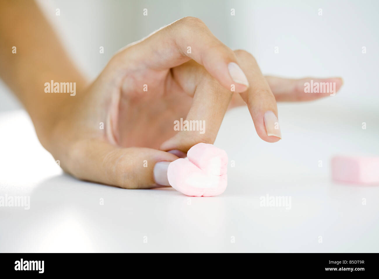 Donna di mano colpetti marshmallow cuore Foto Stock