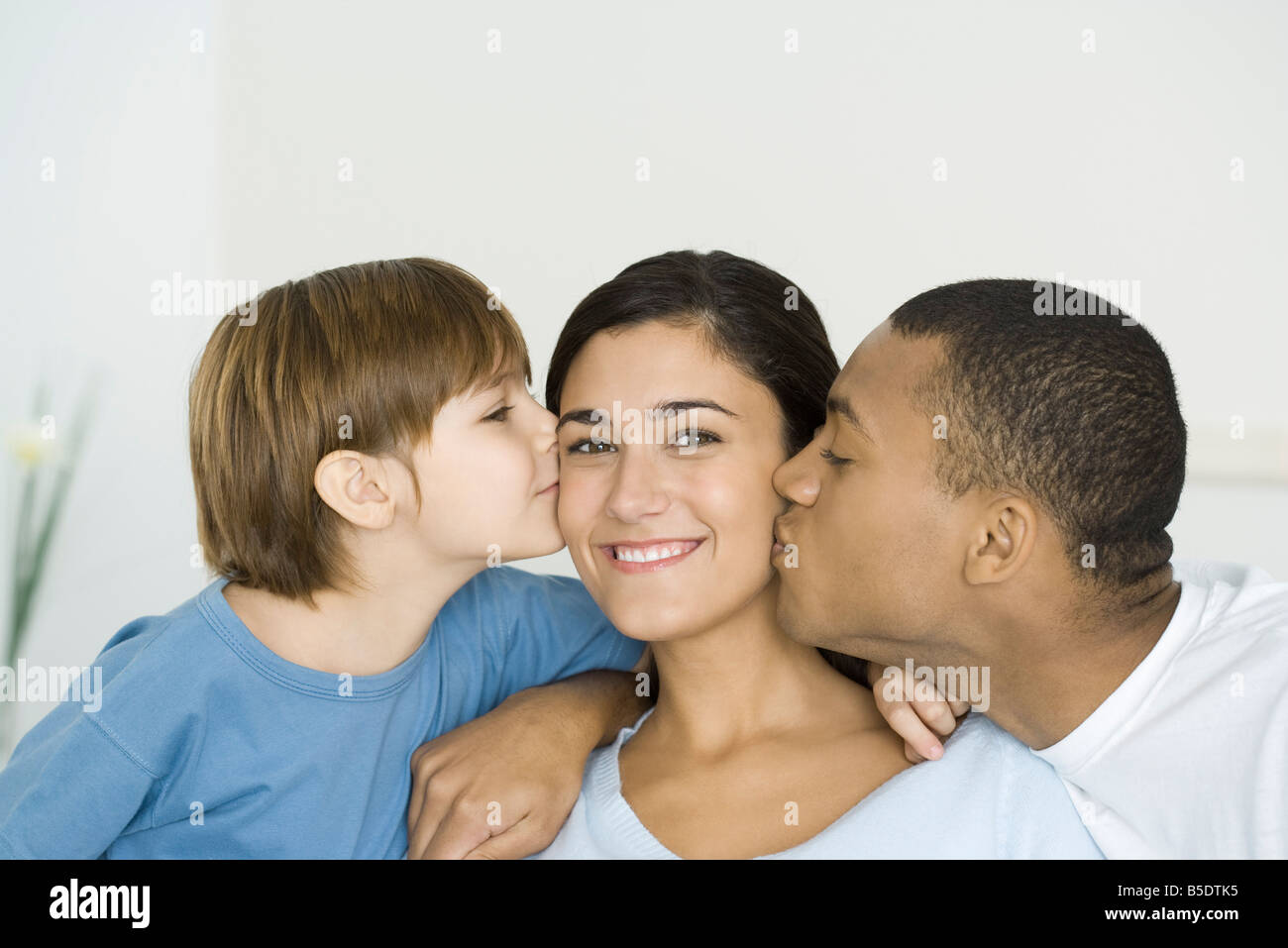 Marito e figlio di baciare una donna guance, Donna sorridente in telecamera Foto Stock