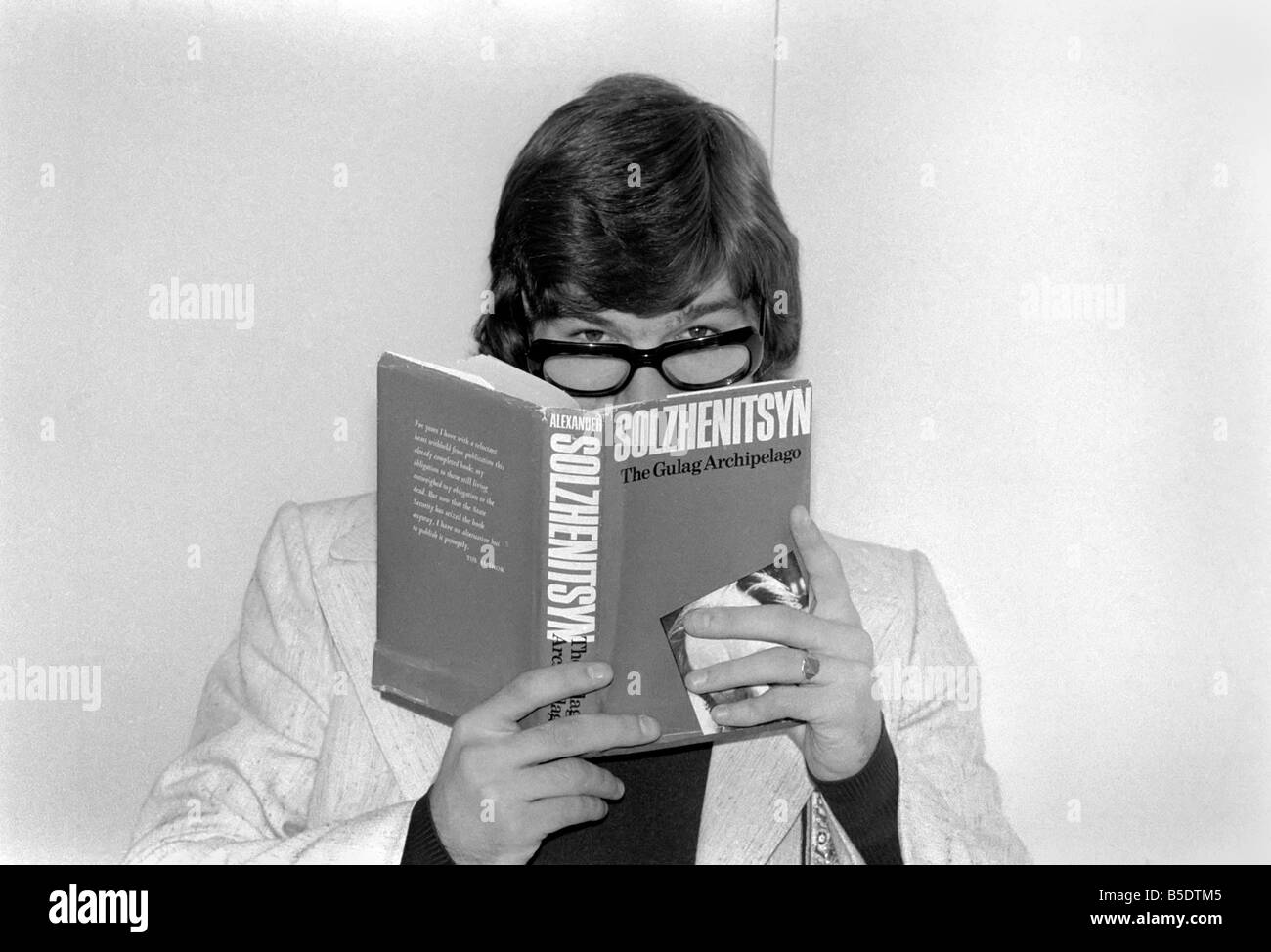 Calciatore inglese Malcolm MacDonald clown intorno con gli occhiali mentre  la lettura "L'arcipelago Gulag" a Heathrow ;Maggio 1975 Foto stock - Alamy