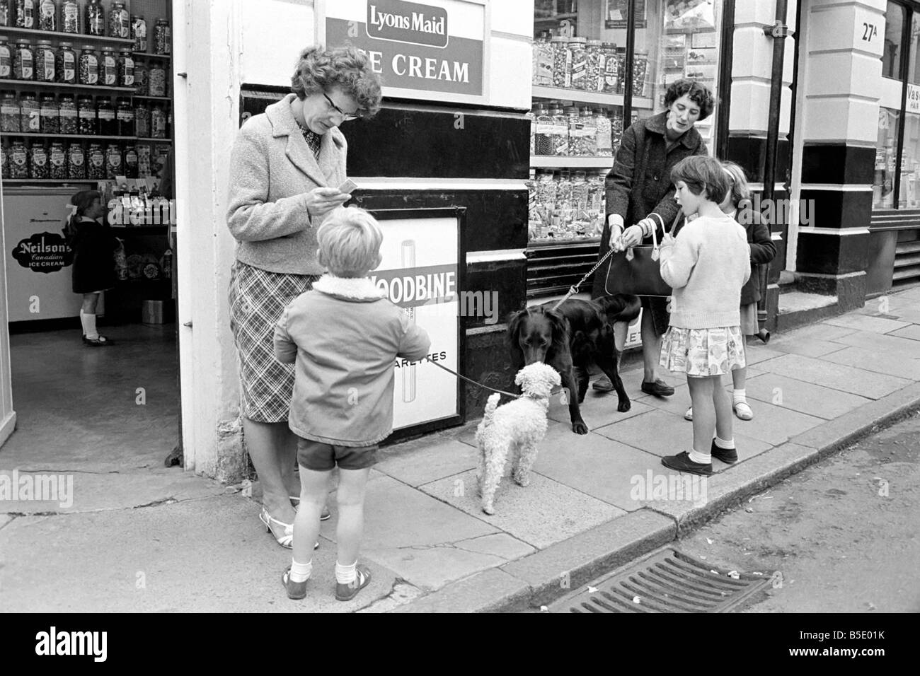 Le scene del cane in Brighton. Scene di persone con i loro cani in Brighton. La nostra immagine mostra; i bambini al di fuori del locale negozio di dolci con i loro cani. Ottobre 1963 Foto Stock