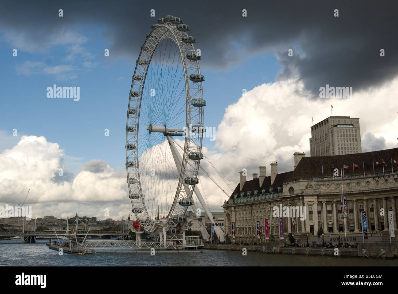 Il London Eye shot attraverso il fiume Tamigi con cielo blu e nuvole scure con una vista complessiva del Southbank Foto Stock