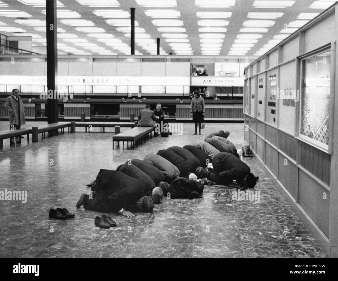 Mentre sono in attesa per il loro volo, musulmani pellegrini verso la Mecca prendere le loro scarpe off, rivolte ad est, inginocchiarsi e pregare. Marzo 1965 Foto Stock