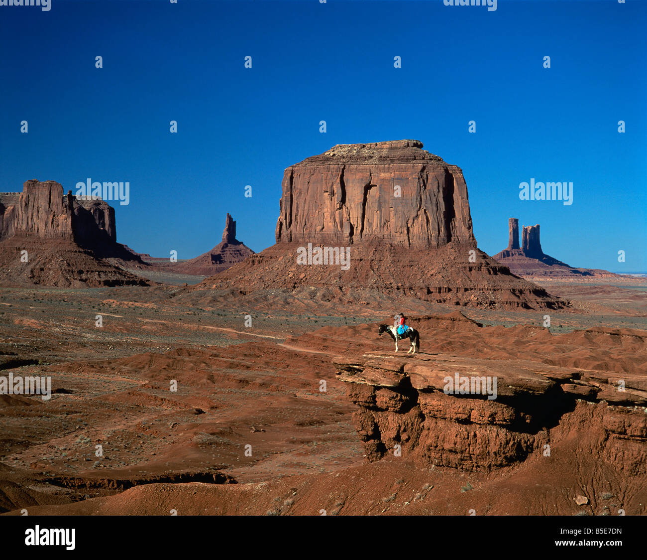 Una donna a cavallo nel deserto con formazioni rocciose causate da fenomeni di erosione in background in Monument Valley Arizona USA UN Foto Stock