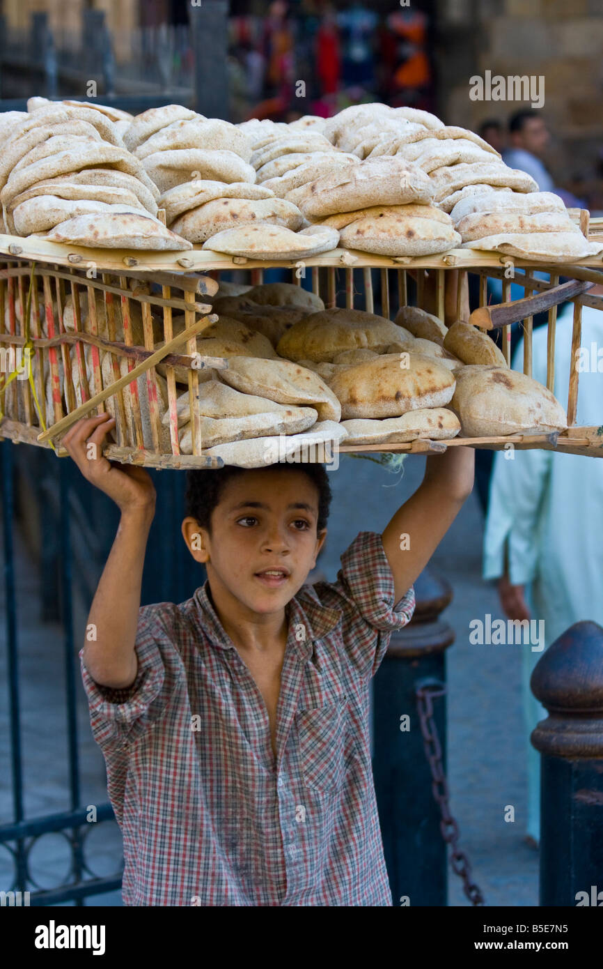 Ragazzo la vendita di pane fresco per le strade de Il Cairo Islamico Egitto Foto Stock