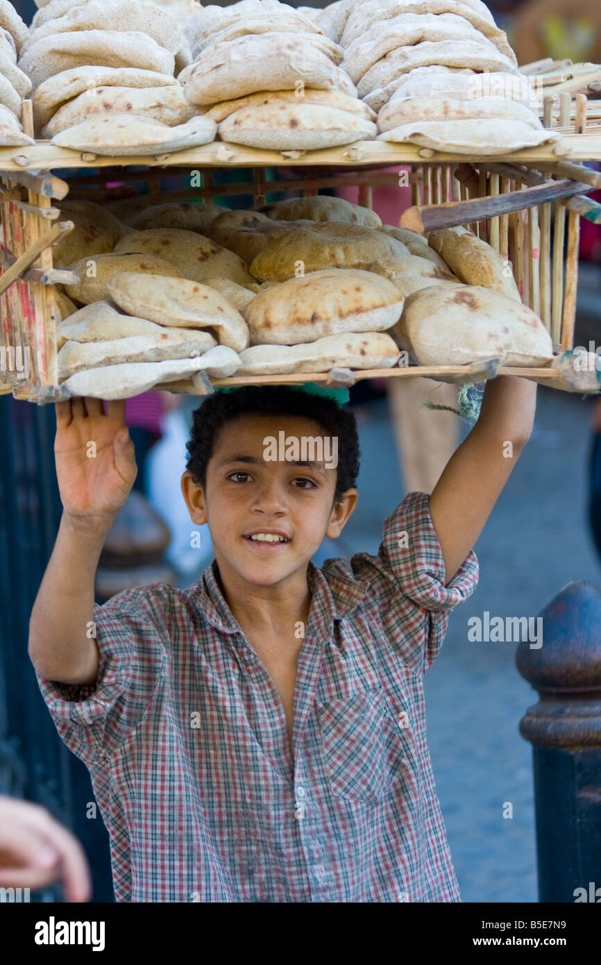 Ragazzo la vendita di pane fresco per le strade de Il Cairo Islamico Egitto Foto Stock