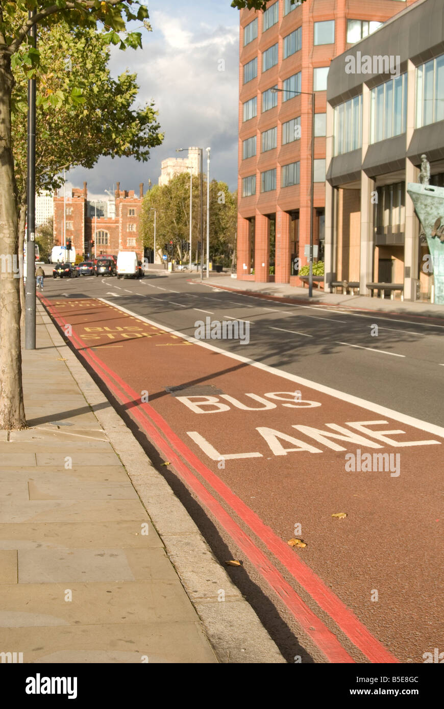 Una immagine di una corsia degli autobus di Londra prese da un percorso con edifici in background e gli alberi sul lato sinistro. Foto Stock