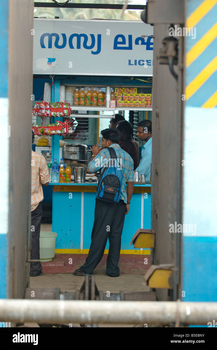 India Kerala, Ernakulum. Indian man aventi un tè presso un tipico piccolo tea-stallo in una stazione ferroviaria. Foto Stock