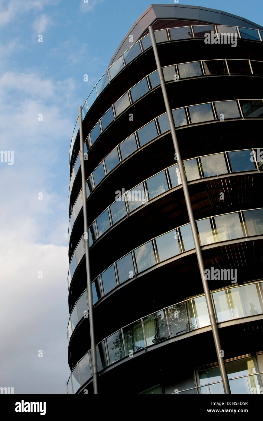 Un'immagine cercando un moderno edificio torre con un sacco di balconi in vetro con cielo blu e nuvole dietro di essa Foto Stock