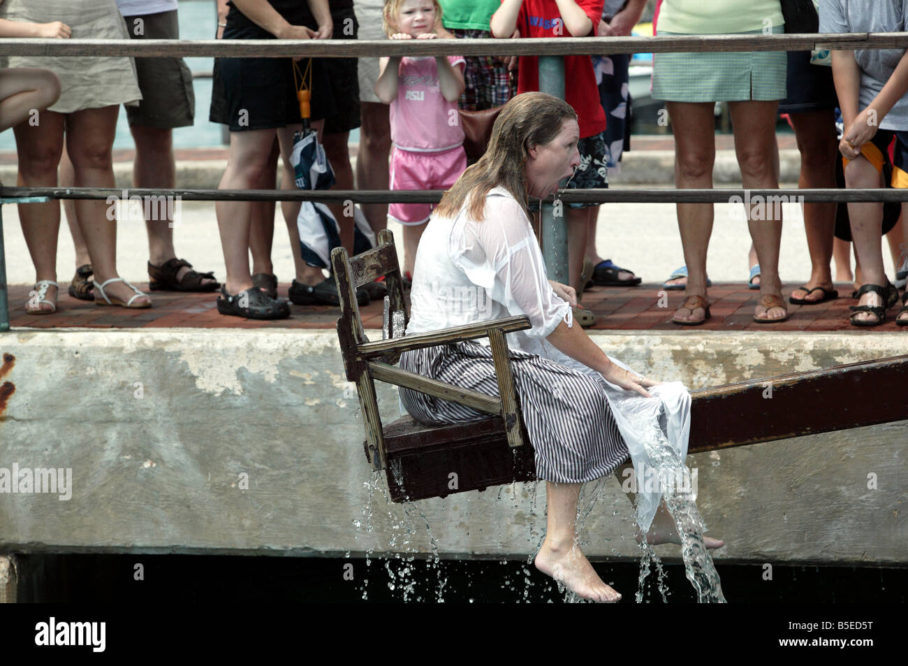 Rievocazione storica in St Georges, Bermuda, mostra una donna essendo si chinò in porto per essere un gossip Foto Stock