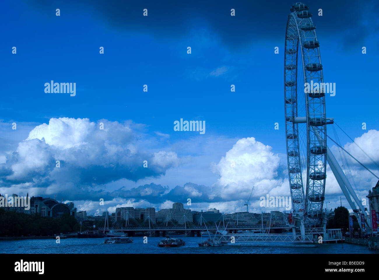 Il London Eye shot da Westminster Bridge con cielo blu e nuvole scure con una vista complessiva del Southbank Foto Stock