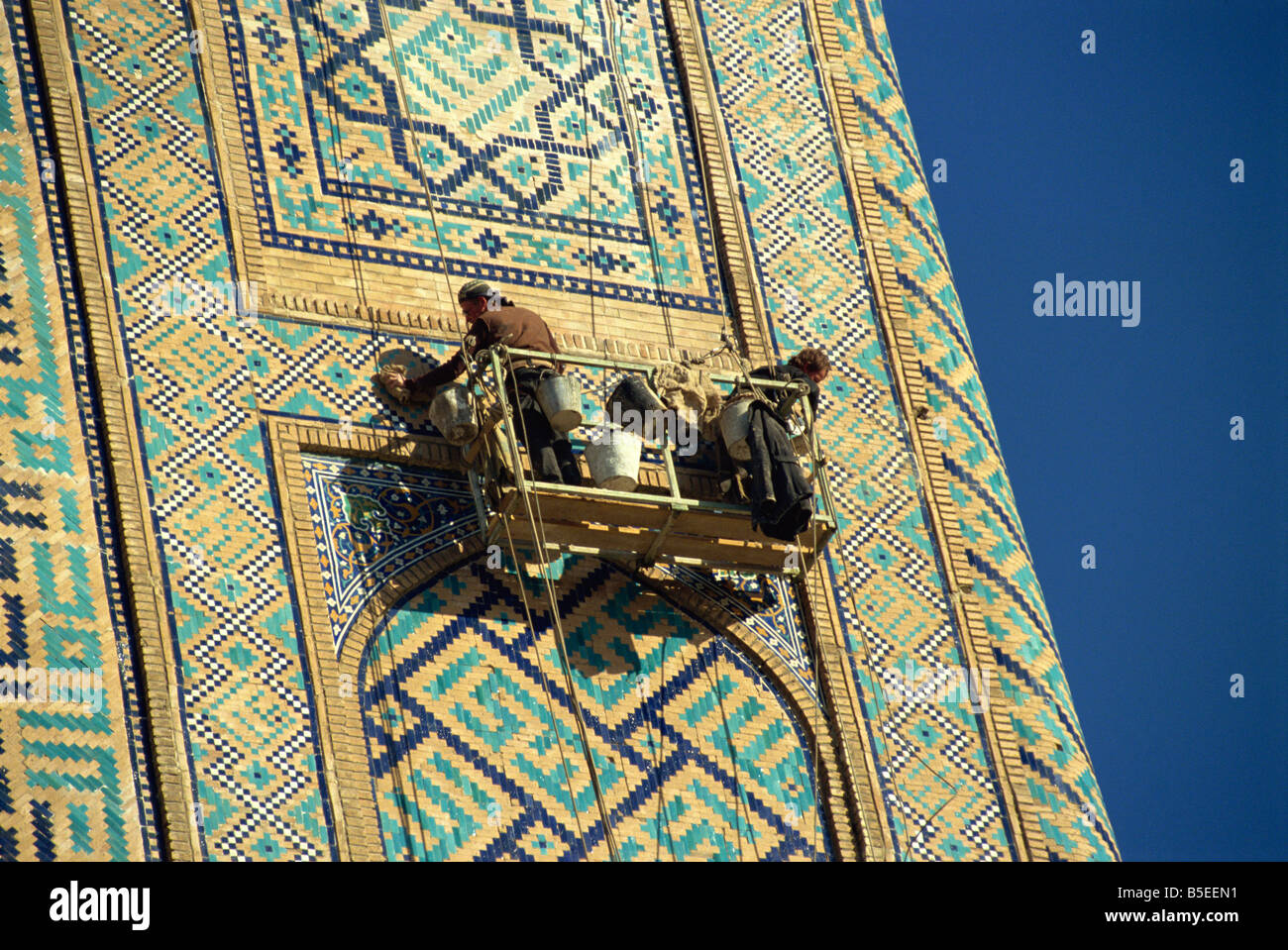 Lavoratori in base riammodernando il XVII secolo Sher Dor Madressa, Registan Square, Samarcanda, Uzbekistan in Asia centrale Foto Stock