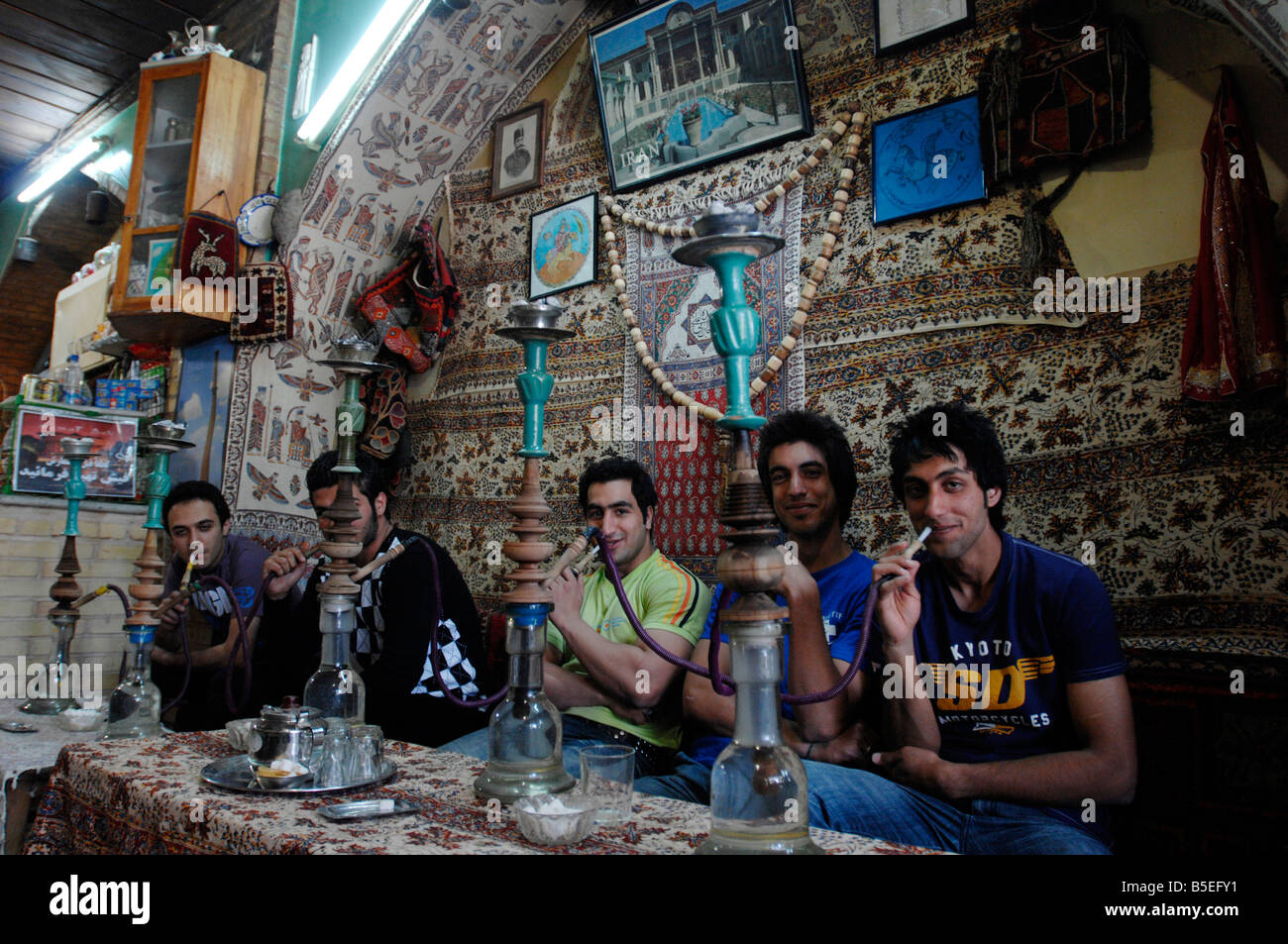 Giovani iraniani maschi i visitatori a Esfahan godetevi un qualyan waterpipe in theChehel Sotun Palace teahouse Foto Stock