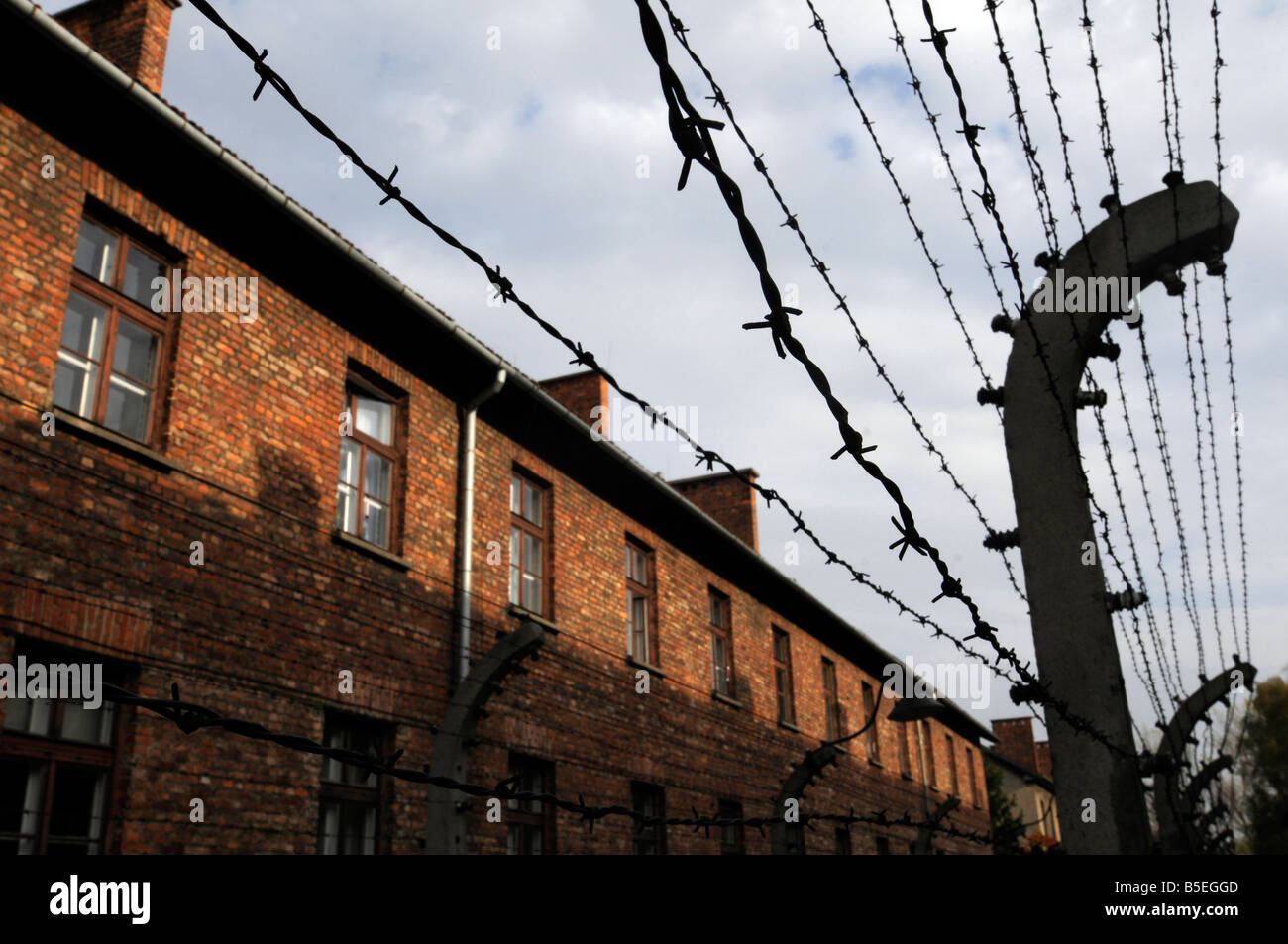 Vista del filo spinato con edifici di Auschwitz lo sterminio nazista camp in background. Foto Stock