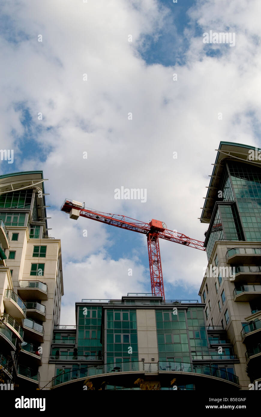 Un immagine guardando fino ad un moderno blocco di appartamenti a Londra con il blu del cielo di nuvole sopra. Una grande gru rosse torri dietro. Foto Stock