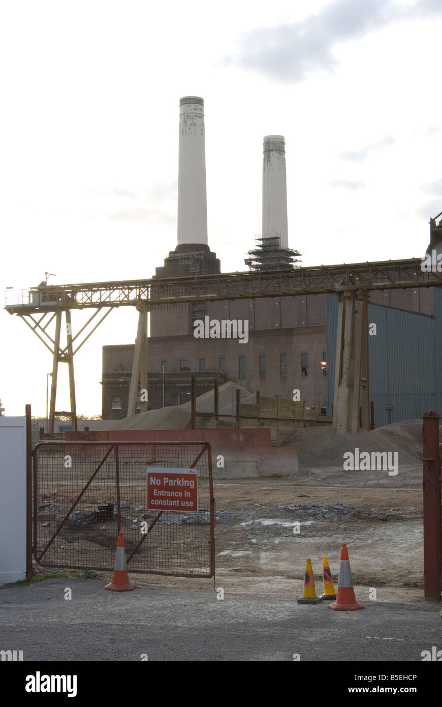 L'ingresso ad un sito di lavoro accanto a Battersea Power Station che mostra due camini e pali di ghiaia sul terreno Foto Stock