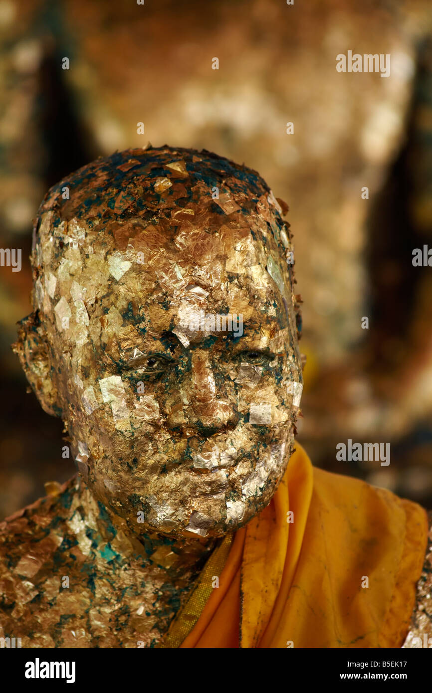 Devoti buddisti applicare strati di foglia oro su Buddha e santi monaci statue per merito di guadagno. Foto Stock