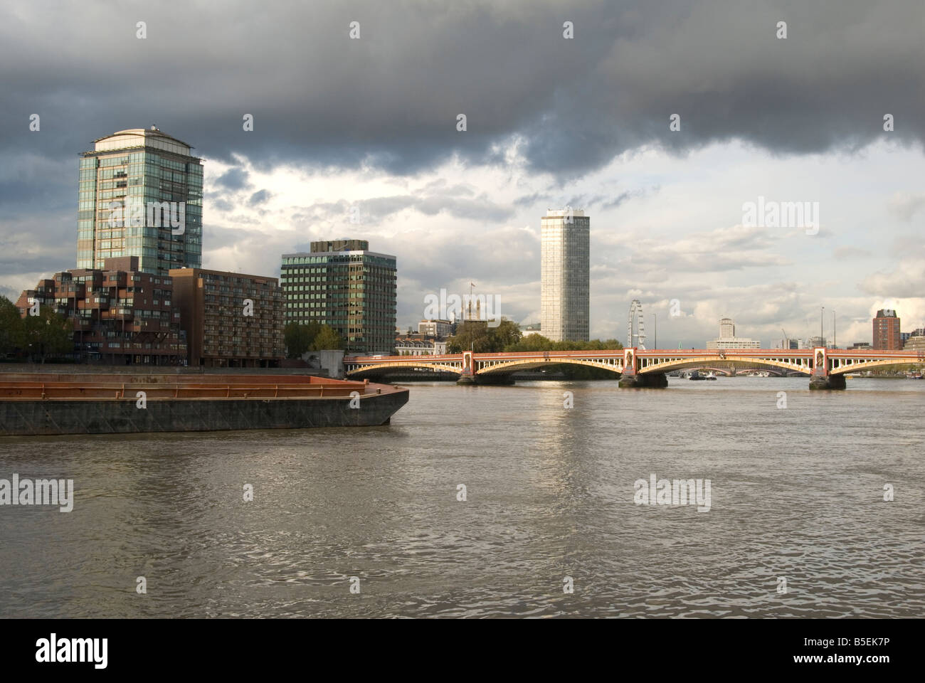 Un'immagine cercando di fronte al Tamigi in alcuni edifici con un contenitore galleggiante in barca e un ponte passando attraverso il fiume Foto Stock