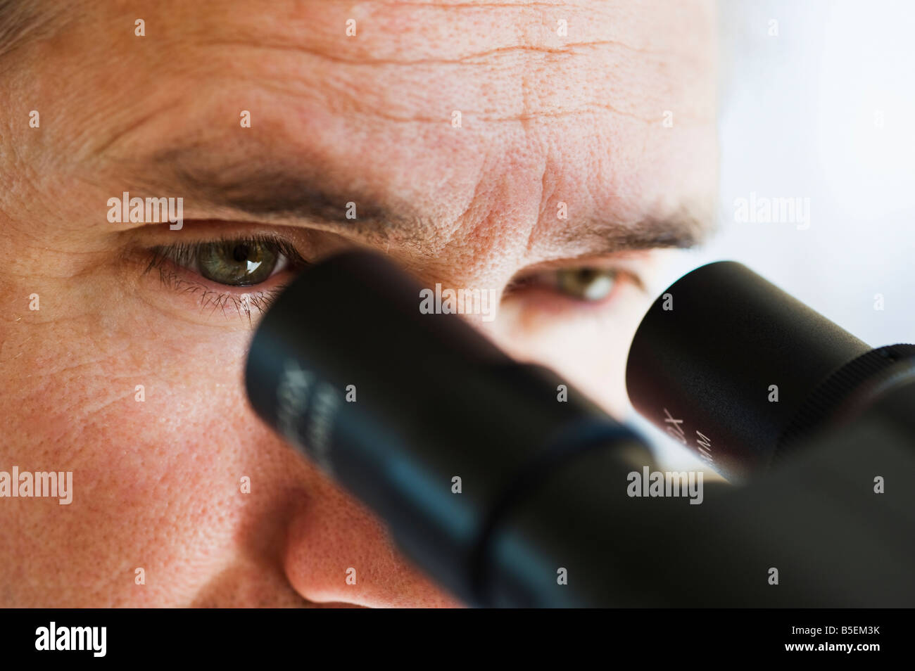 Close up di uomo di occhi guardando attraverso il microscopio Foto Stock