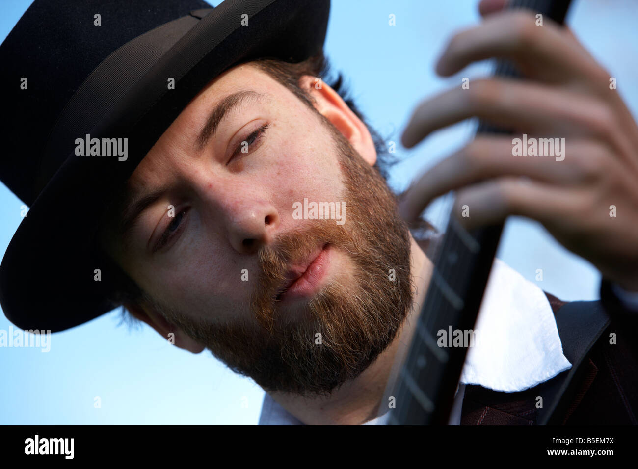 Barbuto 20s uomo a suonare la chitarra all'aperto Foto Stock