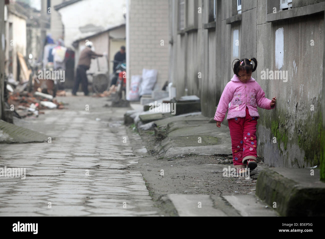 Un giovane annoiato ragazza asiatica camminando lungo una parete, Suzhou, Cina Foto Stock