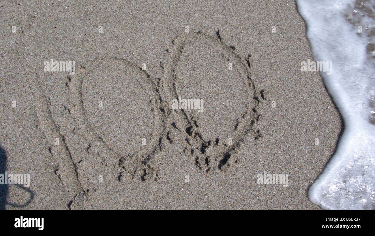 Spiaggia di sabbia con 100 scritto nella sabbia con wave Foto Stock